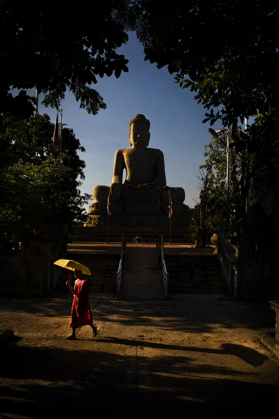 Después de estudiar en un lugar tranquilo cerca de la estatua de Buda, un monje regresa a su habitación bajo la sombra de su paraguas.