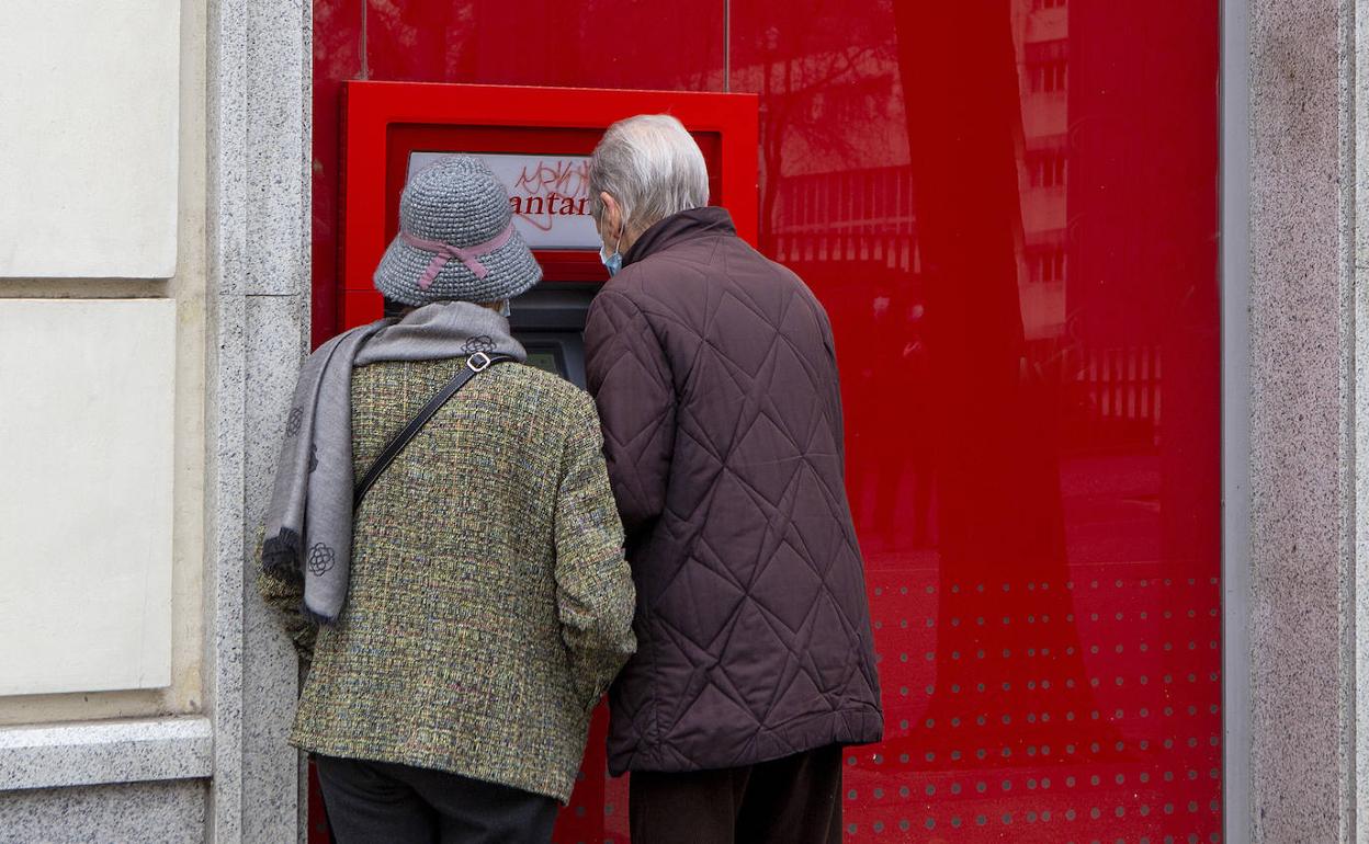 Dos clientes en un cajero automático a pie de calle.