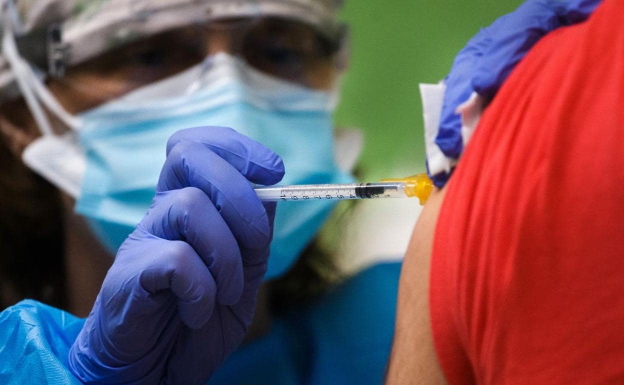 Imagen de un sanitario inoculando una vacuna contra la Covid a un joven.