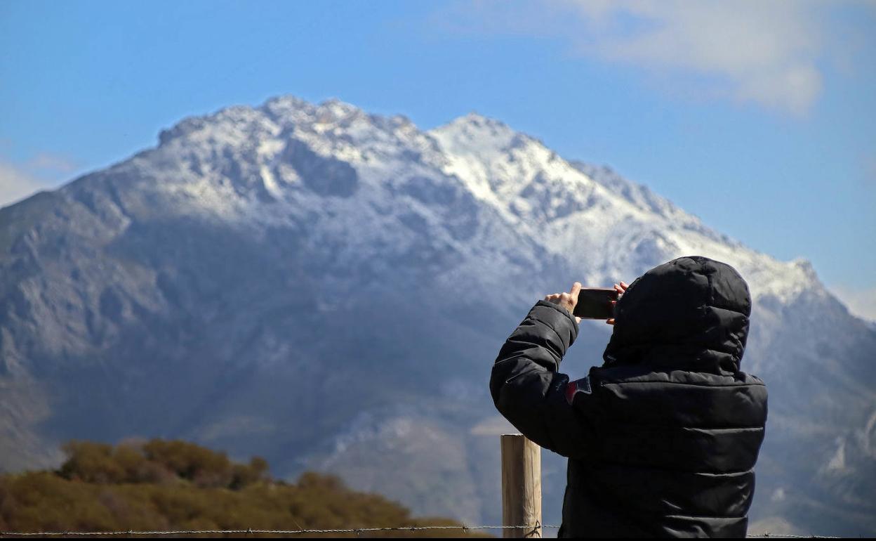 Una mujer fotografía la nieve en los picos de la montaña central. 