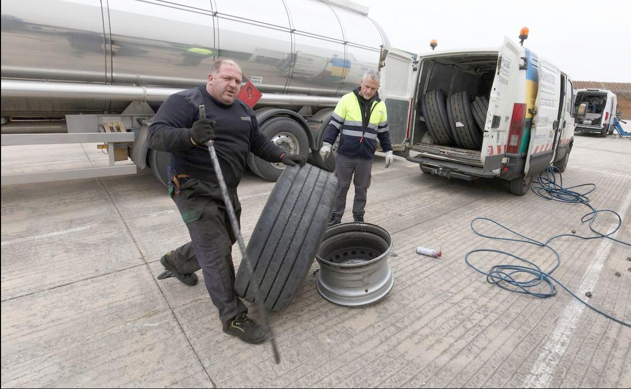 Dos mecánicos proceden a reparar los vehículos con las ruedas cortadas por los piquetes. 