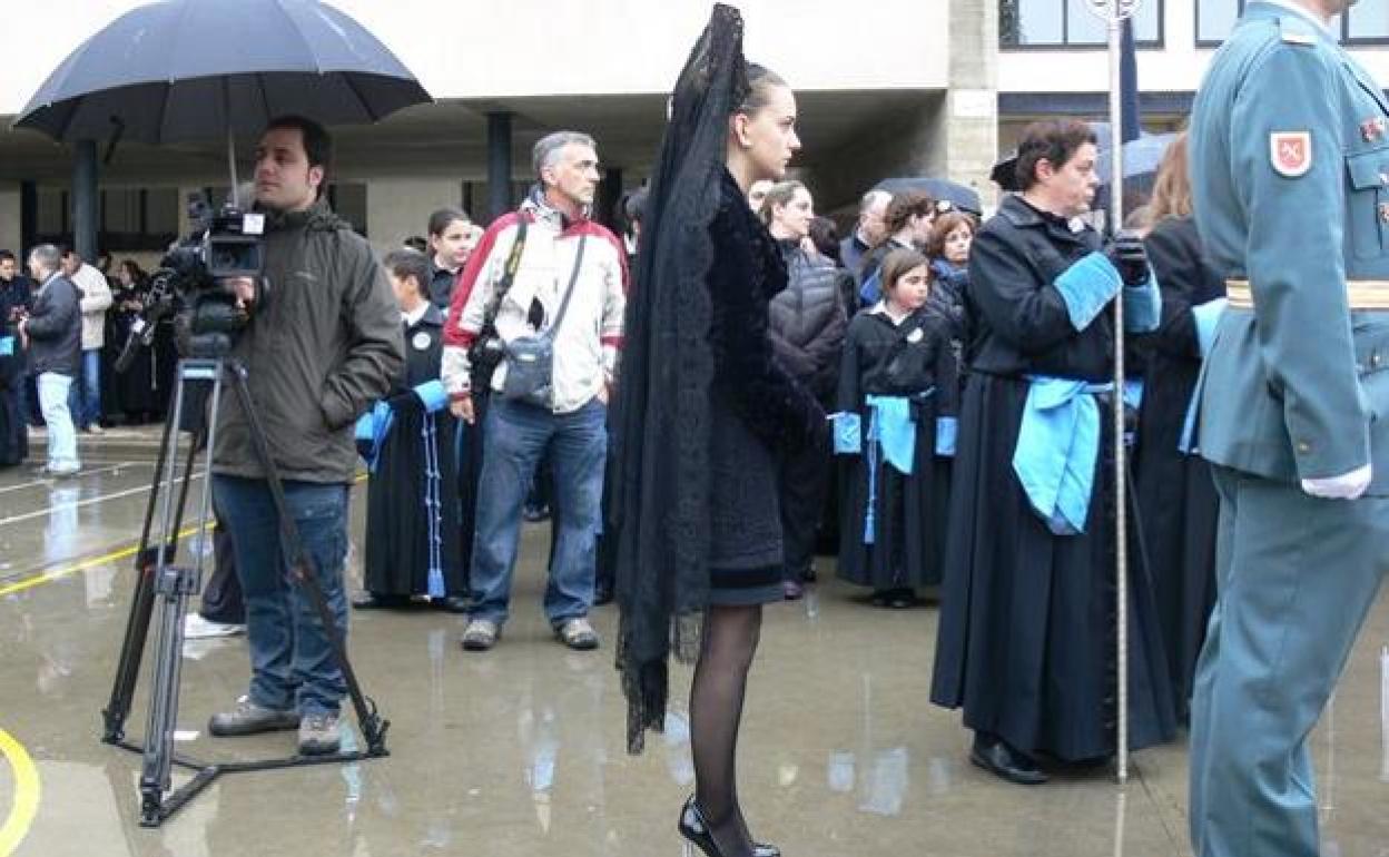 Una manola trata de aguantar bajo la lluvia a la espera de la salida de una procesión.