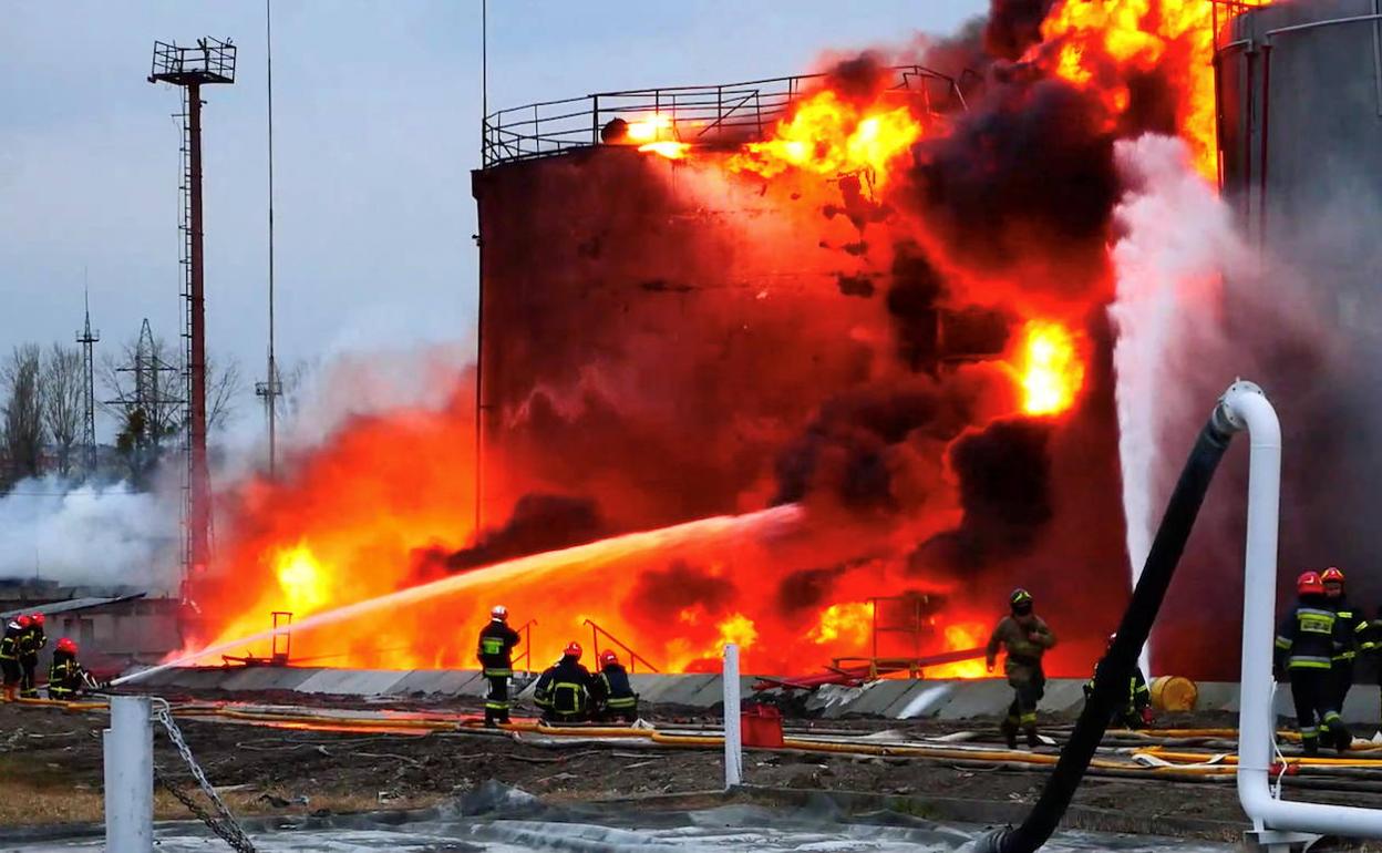 Los bomberos intentan sofocar el fuego tras impactar un misil ruso de largo alcance en un almacén de combustible de Leópolis. 