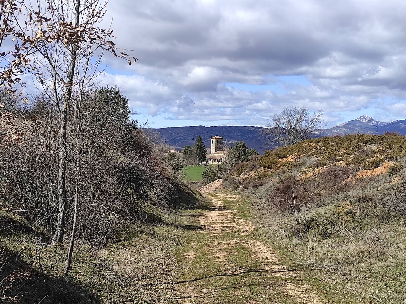 El Viejo Camino entre la Acisa y Barrillos de las Arrimadas. Al fondo, encuadrada en la Puerta Galicia, columbramos la airosa torre de la iglesia parroquial de Santa Marina.