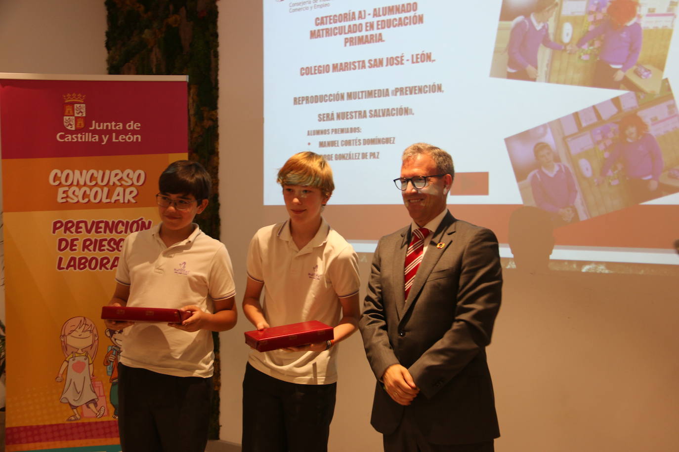 El consejero de Industria, Comercio y Empleo, Mariano Veganzones, entrega a los alumnos de primaria Manuel Cortés y Jorge González de Paz de este colegio leonés el galardón por su vídeo en el que repasan la importancia de prevenir en el colegio yen el trabajo para mejorar la seguridad.