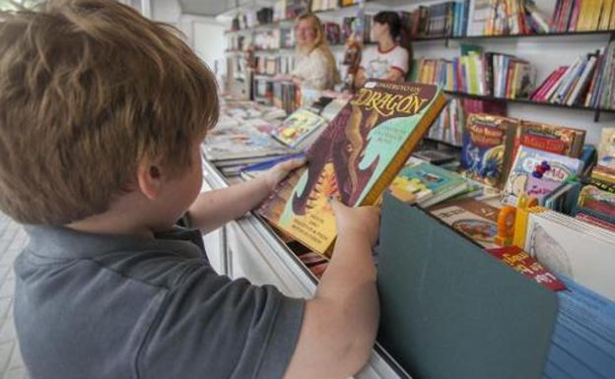 Un niño recoge un ejemplar en la Feria del Libro de León.