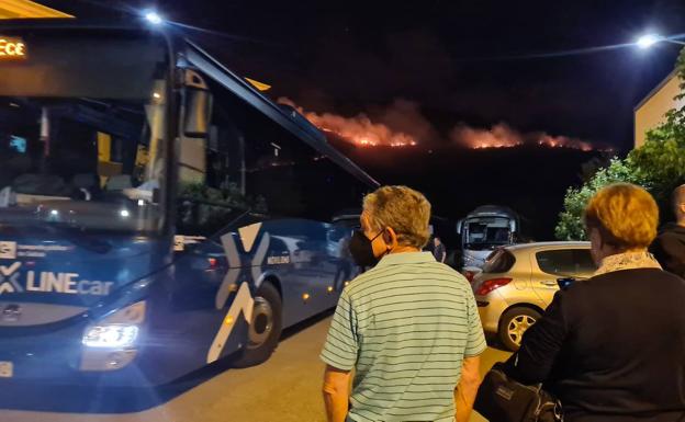 Vecinos de San Pedro ante la llegada de autobuses por una posible evacuación y sin quitar los ojos del fuego que se observa al fondo de la imagen. 