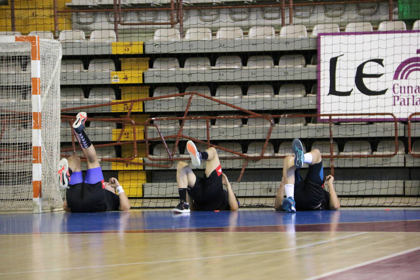 La plantilla del Ademar realiza flexiones en medio de la cancha del Palacio de los Deportes. 