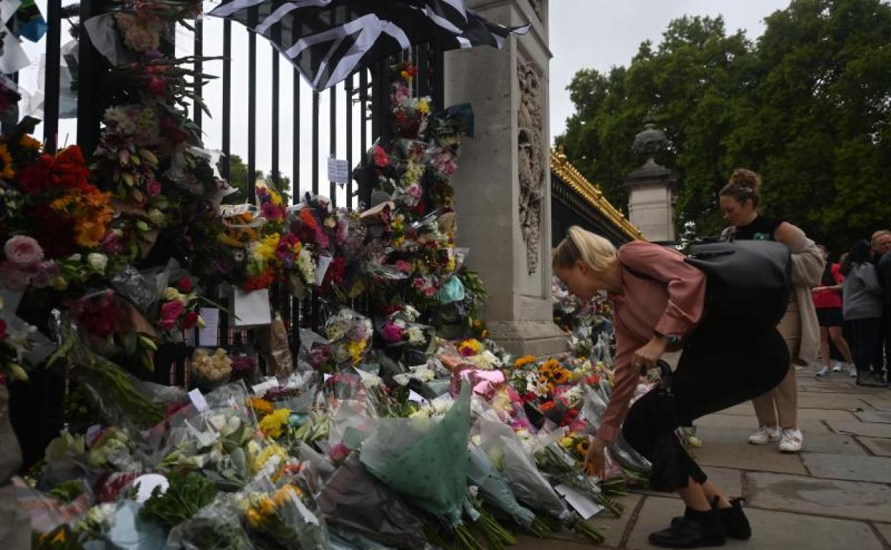 Una mujer deposita un ramo de flores en el palacio de Buckingham. 