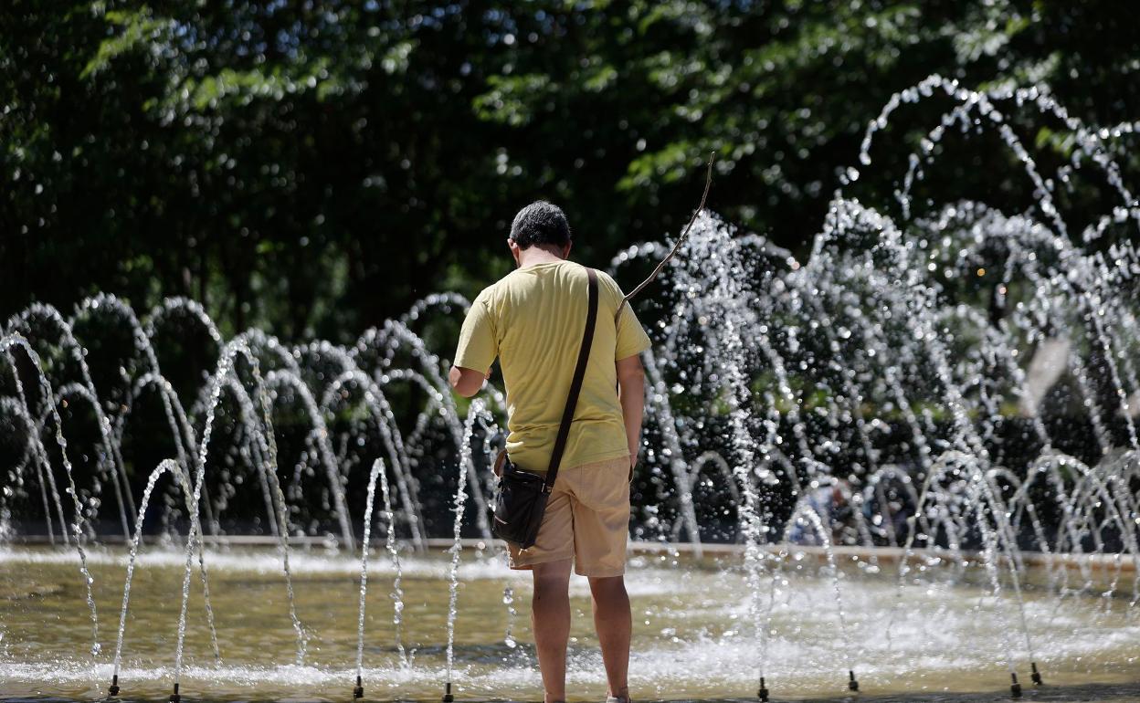 Un hombre se refesca cerca de una fuente.