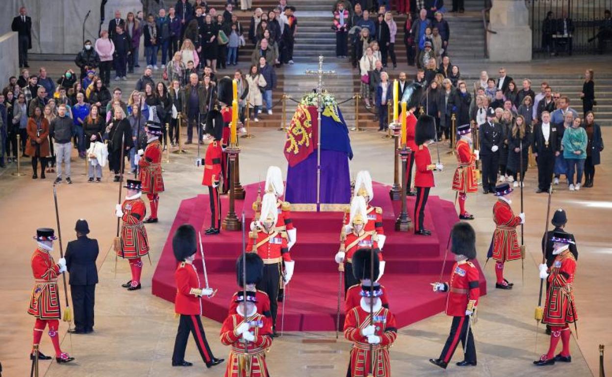 Los guardias reales custodian el féretro de Isabel II mientras miles de personas hacen cola para despedirse de la difunta.