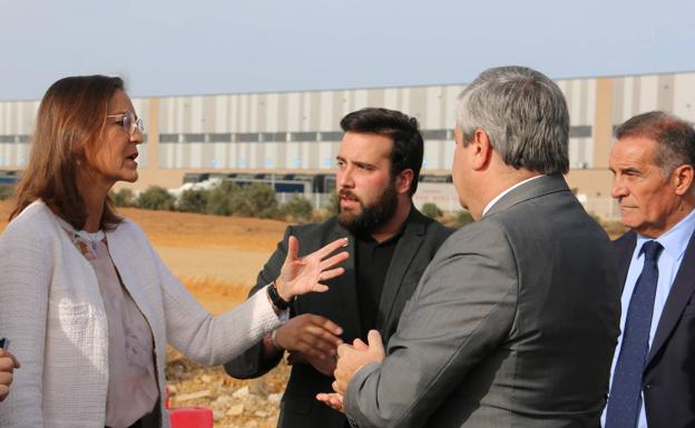 La ministra Reyes Maroto conversa con el alcalde de Villadangos, Alejandro Barrera, delante de la 'playa' que se levantará junto al tramo ferroviario industrial que llega al polígono. 