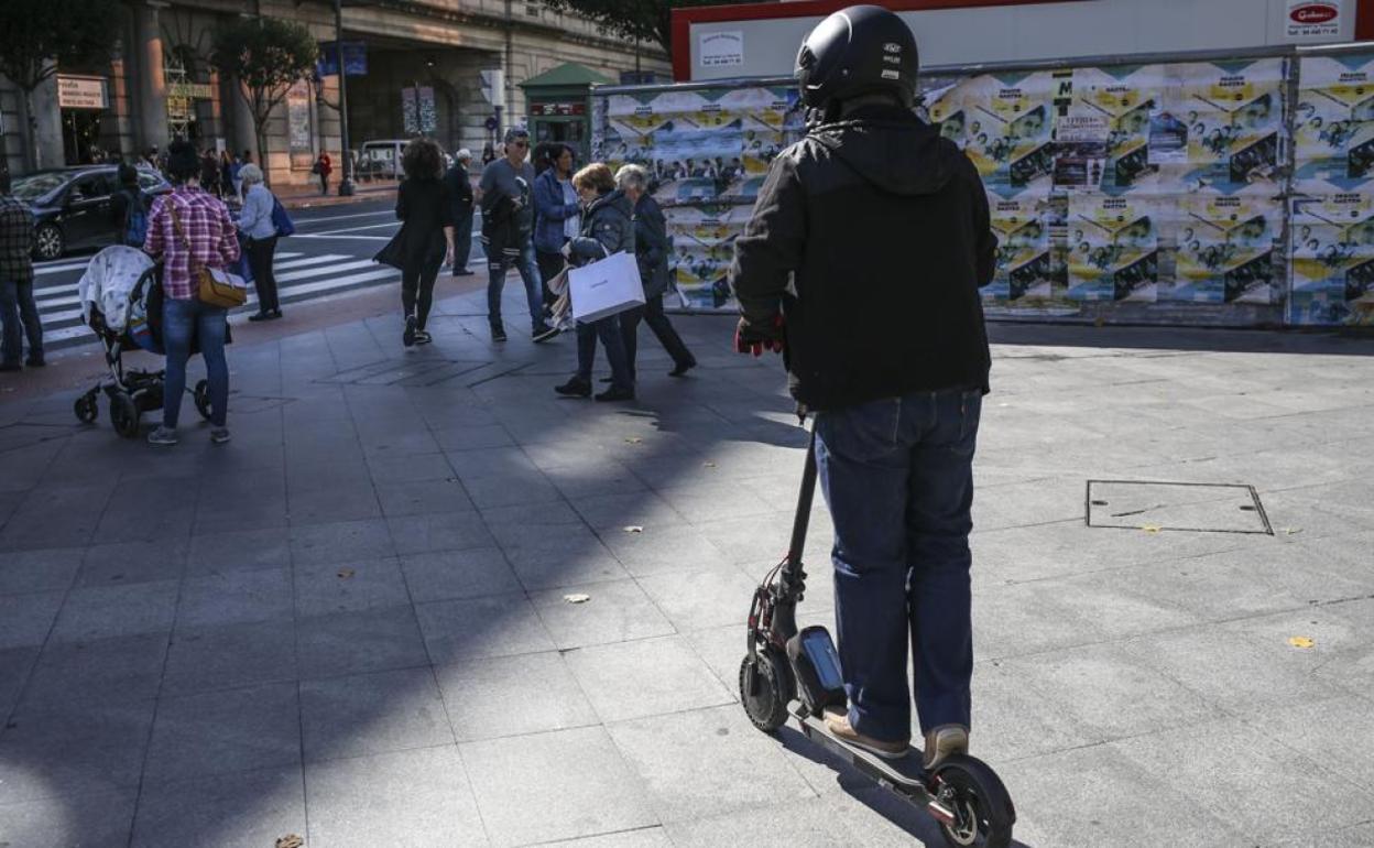 Un patinete eléctrico circulando por la acera en una ciudad española.