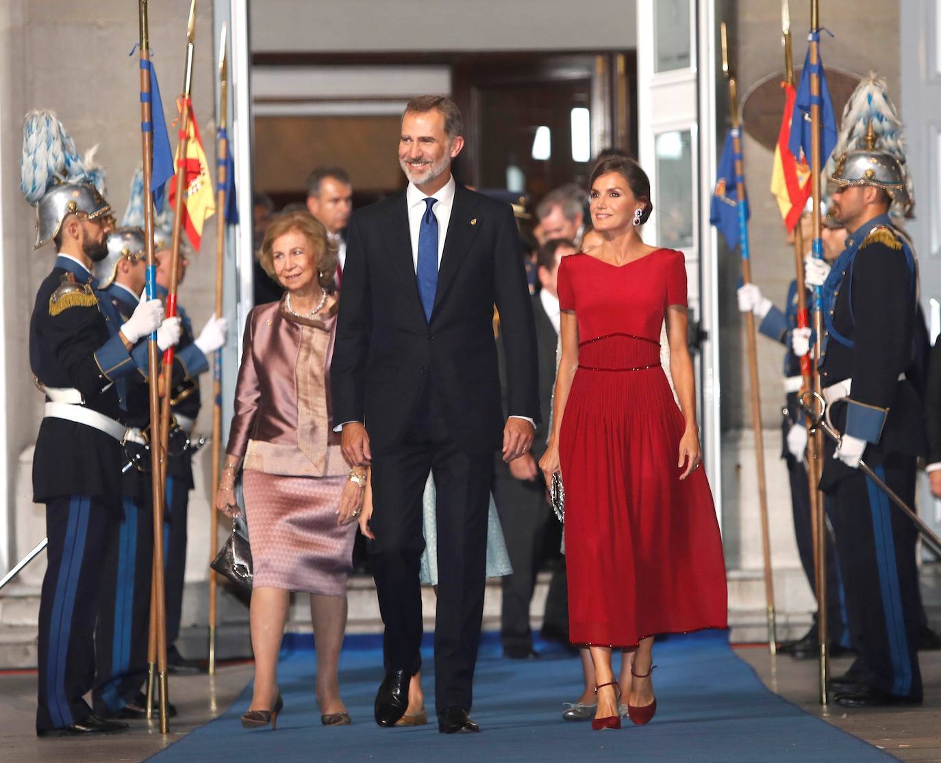 2019. El rojo es el color fetiche de la Reina, pero era la primera vez que lo escogía para el evento en el Teatro Campoamor. El carmesí teñía el sencillo vestido de Felipe Varela en seda. Con el cuerpo entallado, un cerrado escote en uve y unas hombreras ligeramente marcadas, el diseño se abría en una falda de gasa que partía de una cintura de cristales a modo de fajín, a juego con sus zapatos. 