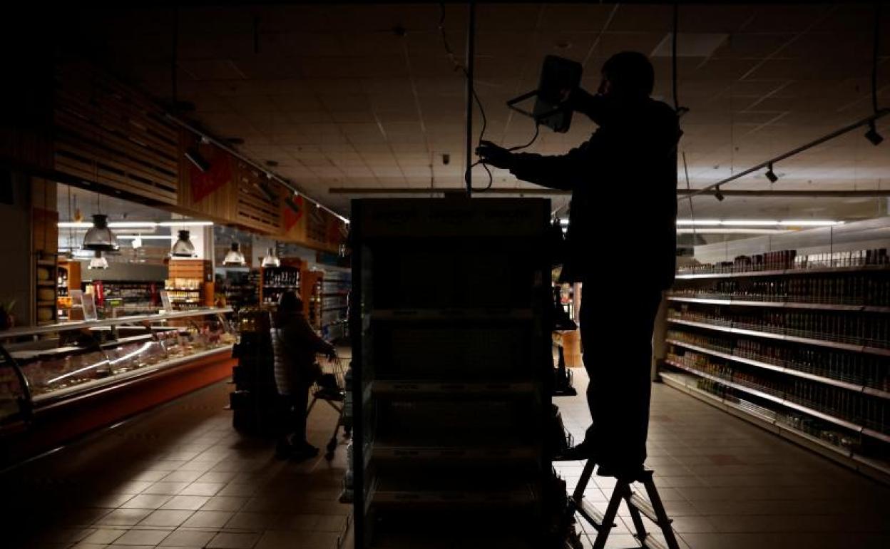 Un trabajador instala una luz alimentada por un generador en un supermercado de Kharkiv a oscuras por un bombardeo ruso. 