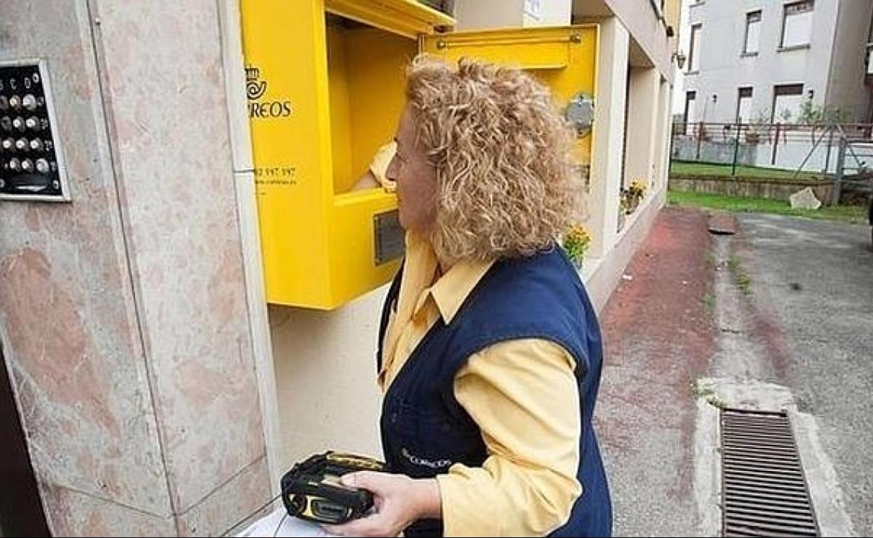 Imagen de una cartera recogiendo el correo en uno de los pueblos de León. 