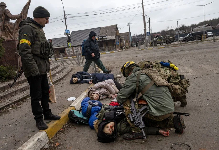 Soldados ucranianos atienden a un grupo de civiles, entre ellos Tetiana Perebyinis y sus dos hijos, que fueron heridos de muerte por un proyectil de mortero ruso mientras evacuaban de Irpin, Ucrania, el 6 de marzo. También murió un voluntario que ayudaba a la familia. 