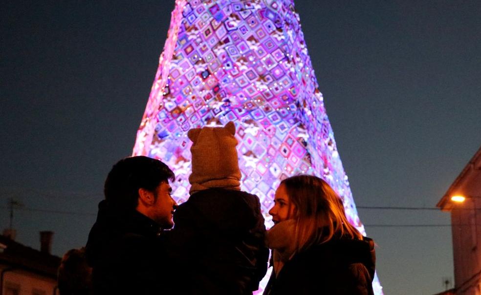 Una familia disfruta de la iluminación del árbol de Navidad de la localidad. 