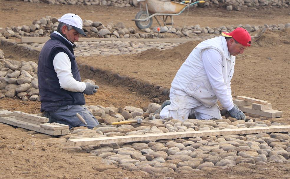 El patio de la portería del Monasterio de Sandoval se reconstruye con los antiguos cantos rodados que los operarios colocan uno a uno. 