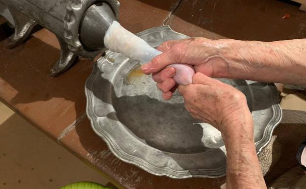 La carne de los embutidos saliendo por la máquina y rellenando la tripa.