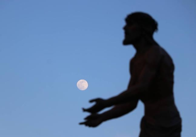 El Santo Cristo del Perdón avanza con la luna de fondo.