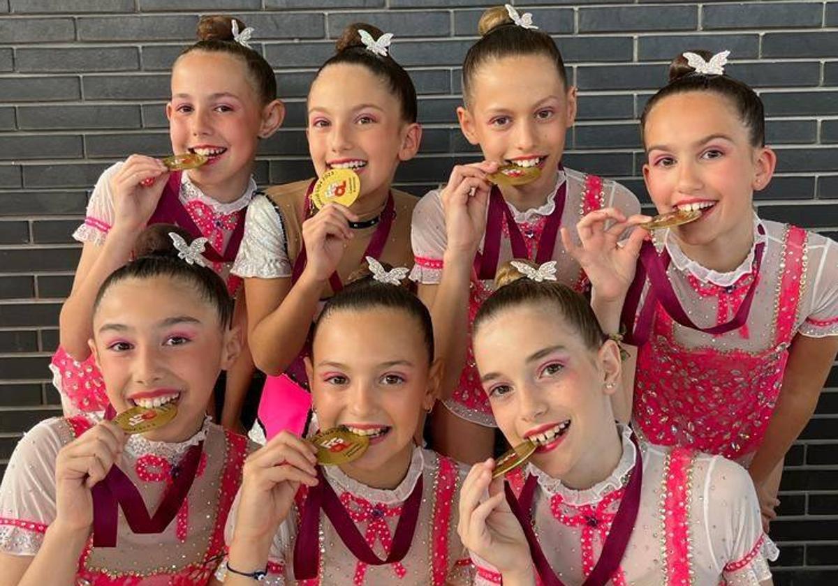 Las gimnastas del Club Ritmo muerden su medalla de oro.