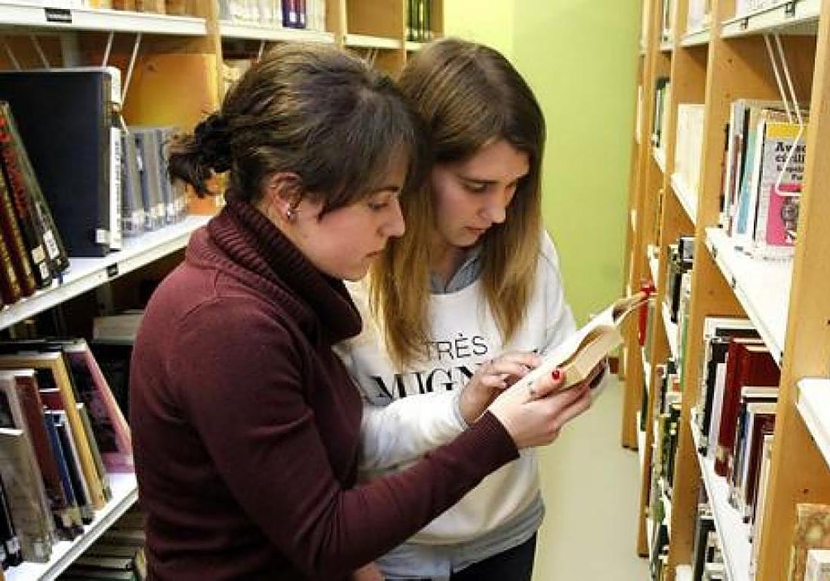 Dos jóvenes consultan un libro.