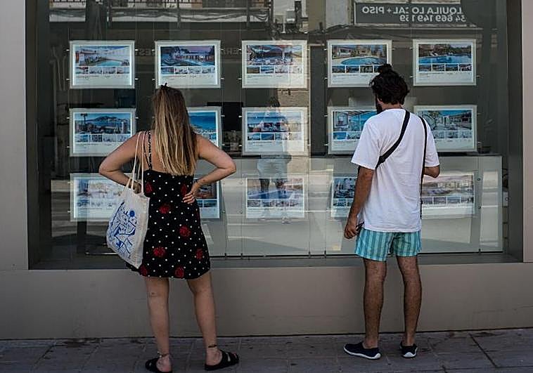 Dos personas revisan las opciones de alquiler de una inmobiliaria.