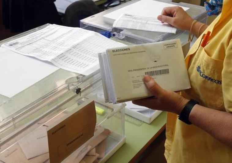 Uan repartidora de Correos introduciendo las cartas en las urnas.