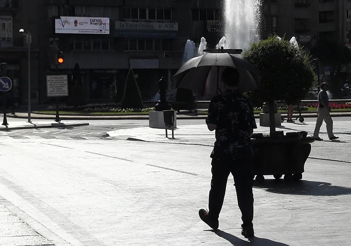 Un joven se protege del sol con un paraguas durante una ola de calor en León.