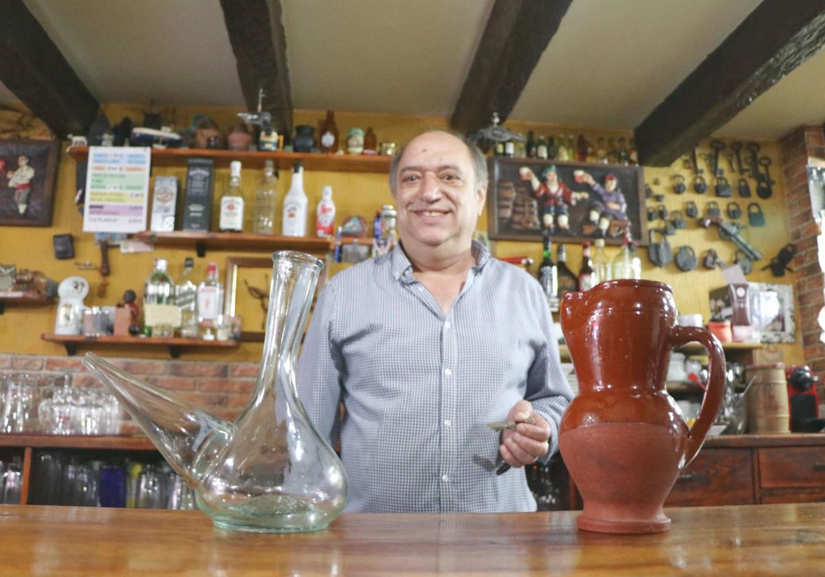 Carlos Gómez posa en su bar, el Mesón Valdevimbre, junto a sus famosos porrones y jarras de barro.