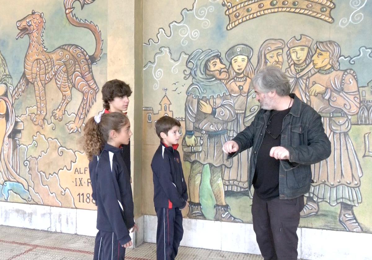 El profesor Jesús Palmero explica a alumnos del colegio Leonés la técnica del mural que Lolo dibujó en este centro.