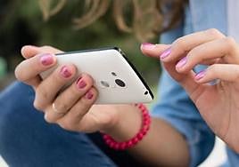 Una joven escribe en su teléfono móvil.