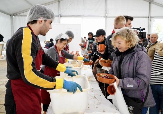 Vecinos y turistas hacen cola para recoger el plato con la degustación de la cecina de chivo.