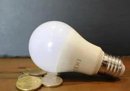 Bombilla sobre monedas que reflleja el precio de la luz.