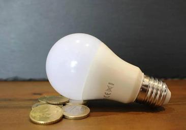 Bombilla sobre monedas que reflleja el precio de la luz.