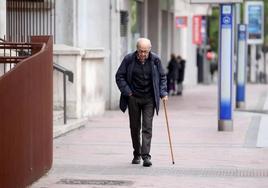 Un hombre pasea por la calle con bastón.