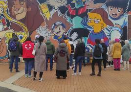Varios inmigrantes observan el mural de la Lastra.