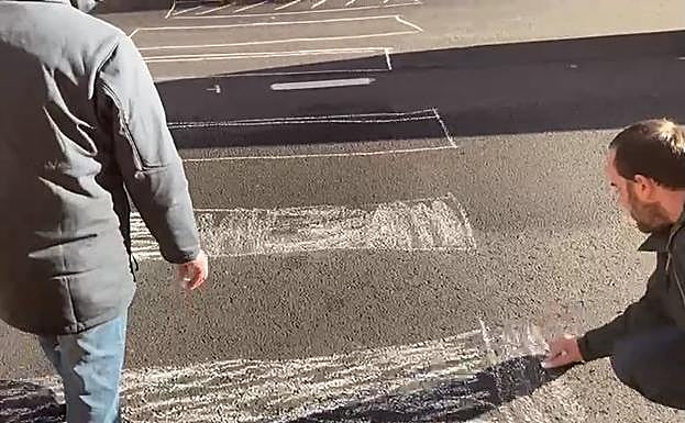 Concejales del PP de Cistierna pintan el paso de peatones de la carretera general del municipio.