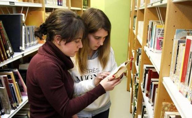 Dos jóvenes leyendo en una biblioteca.