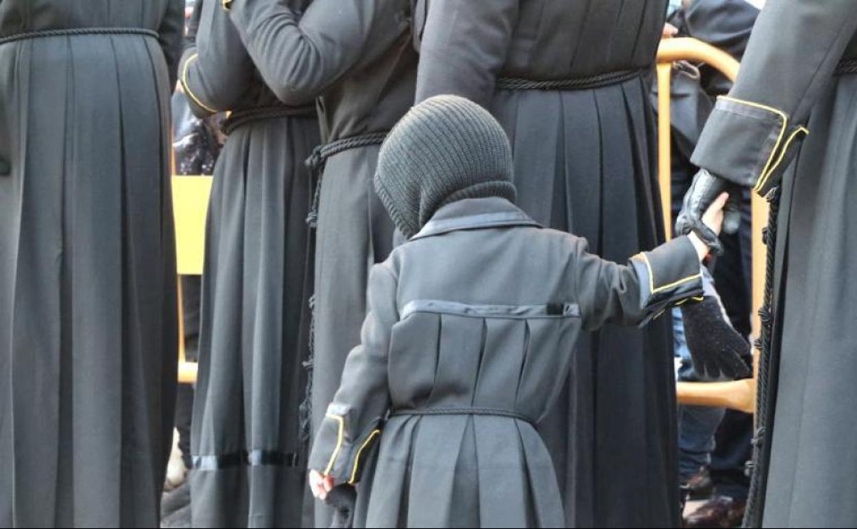 Un joven papón de Angustias camina de la mano de un familiar por las calles de León.