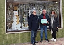 El ganador del primer premio posa frente al escaparate de su tienda.