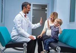 Un niño junto a su médico de cabecera en una consulta.