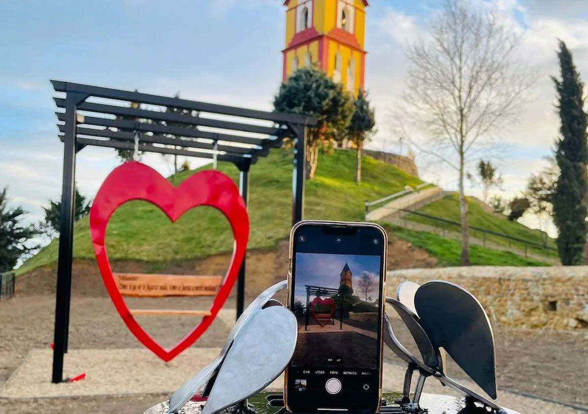 Un columpio con la torre de la iglesia de fondo en el 'Paseo del amor'.