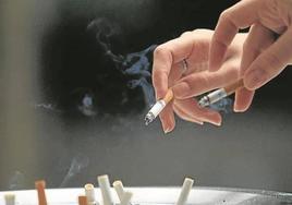Dos fumadores depositan la ceniza de sus cigarros.