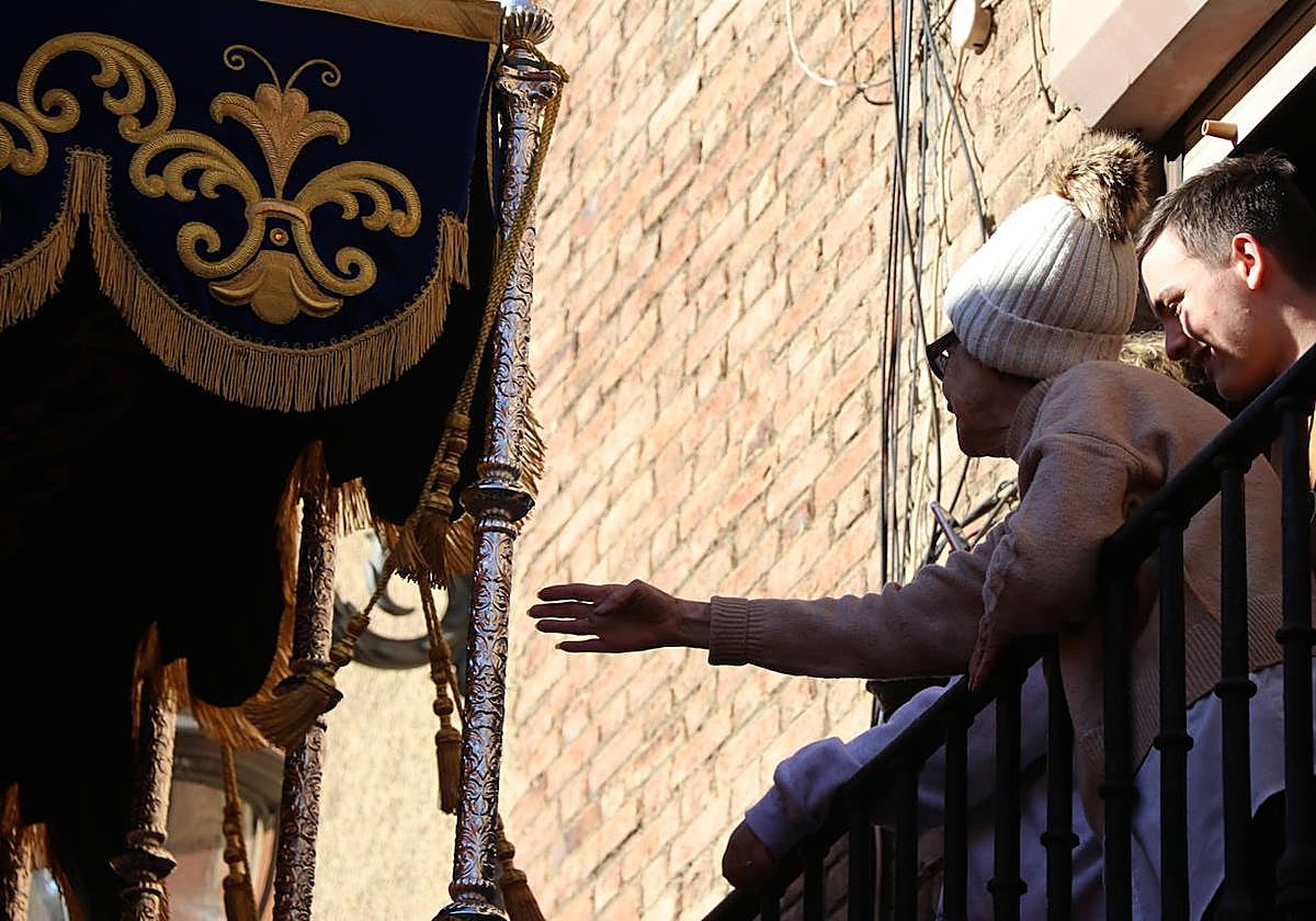 Una mujer trata de tocar el palio de una virgen durante la pasada Semana Santa.