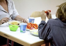 Una madre y su hijo, con muy escasos recursos, se alimentan en un comedor social.