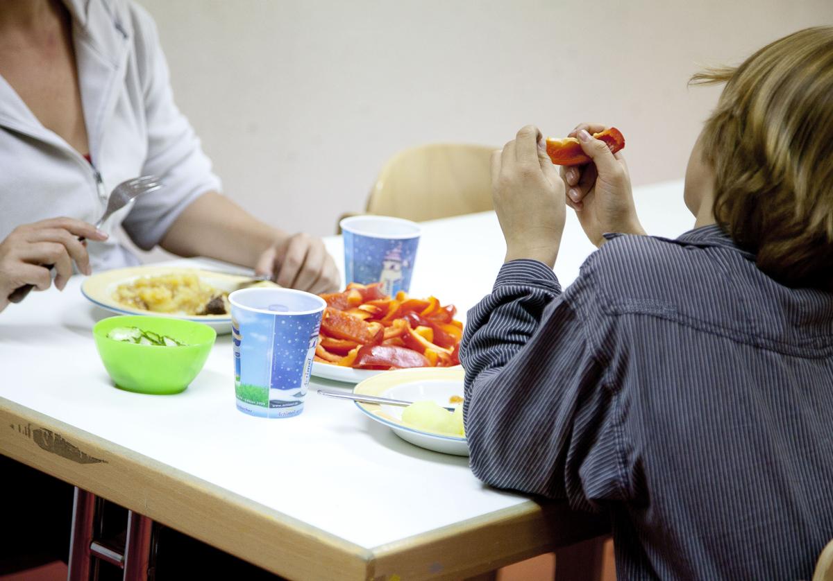 Una madre y su hijo, con muy escasos recursos, se alimentan en un comedor social.