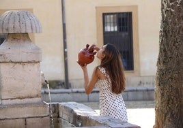 Una joven se refresca bebiendo agua de un botijo en la plaza del Grano.