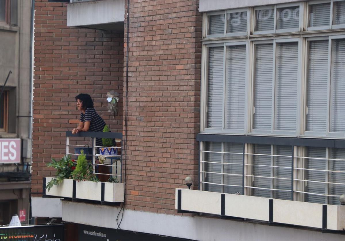 Imagen de una mujer asomada al balcón de su terraza en León.